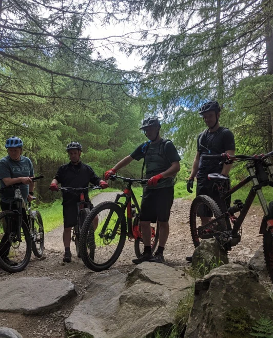 Group of students with mountain bikes taking a break on a forest trail surrounded by trees. Group of students with mountain bikes taking a break on a forest trail surrounded by trees.